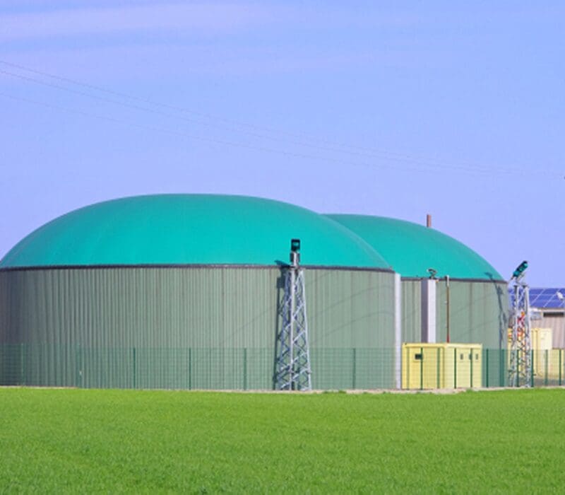 Large green dome-shaped building sitting atop a lush green field, surrounded by a fence and towers